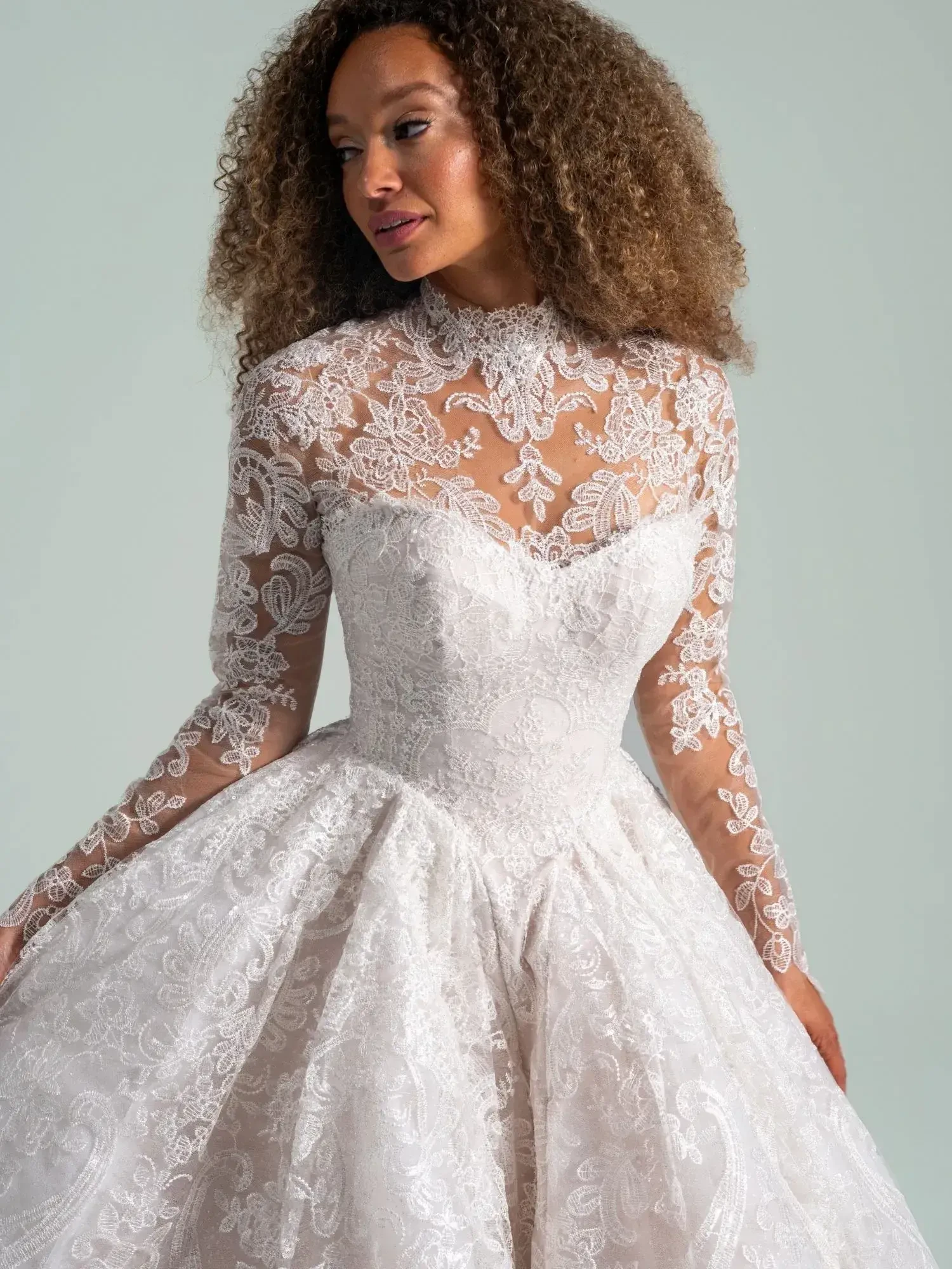 A woman wearing a white wedding dress with lace long sleeves and an intricate lace design.